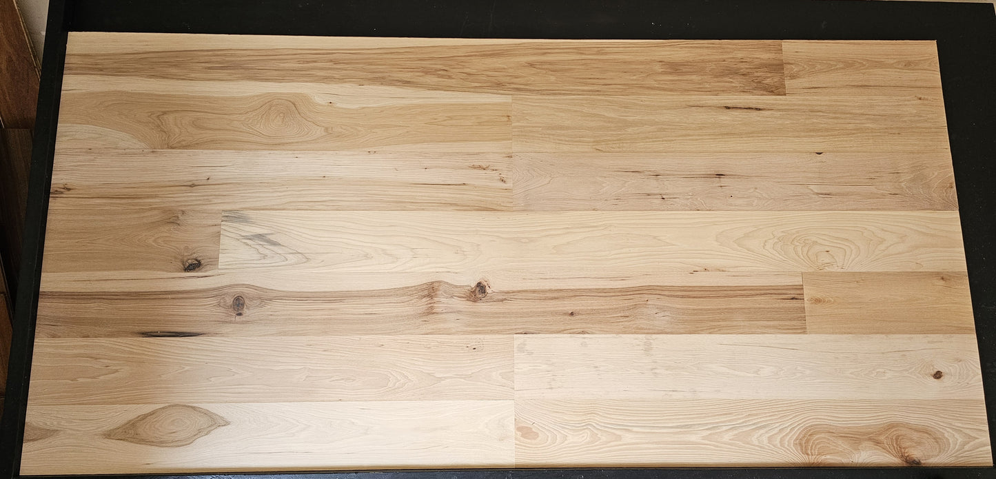 6" x 5/8" Engineered Unfinished Hickory Hardwood Flooring. Shown on a black shooting table. shot from center.