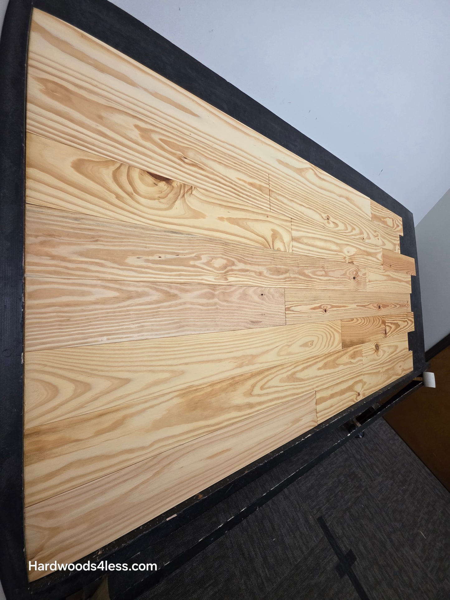5 1/8" x 3/4" Southern Yellow Pine Wire Brushed Natural Solid Hardwood Flooring. Shown on a black shooting table. Shot steep from the left hand side.