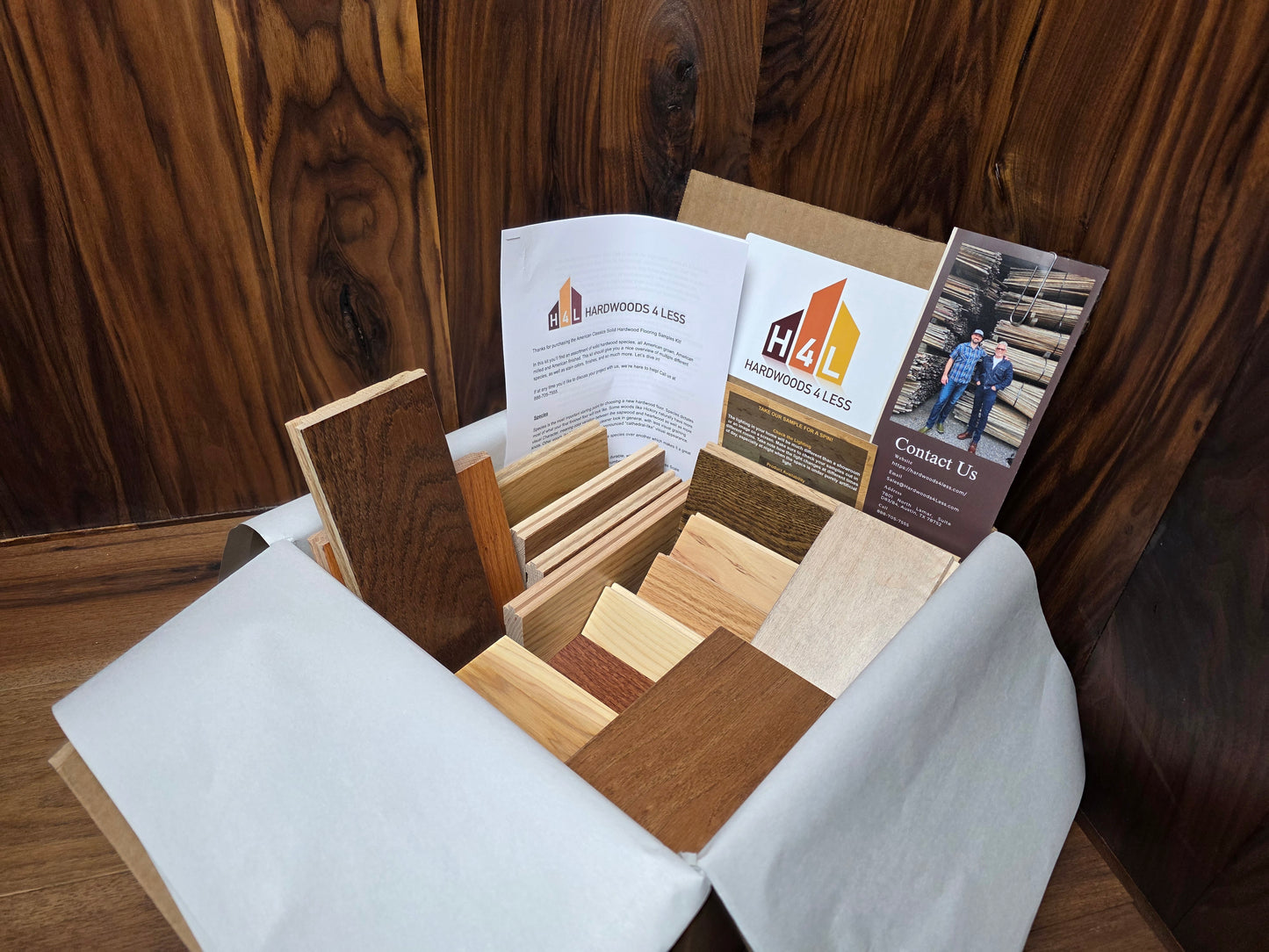 Hardwood Flooring sample box with wood swatches and brochures on a wooden surface