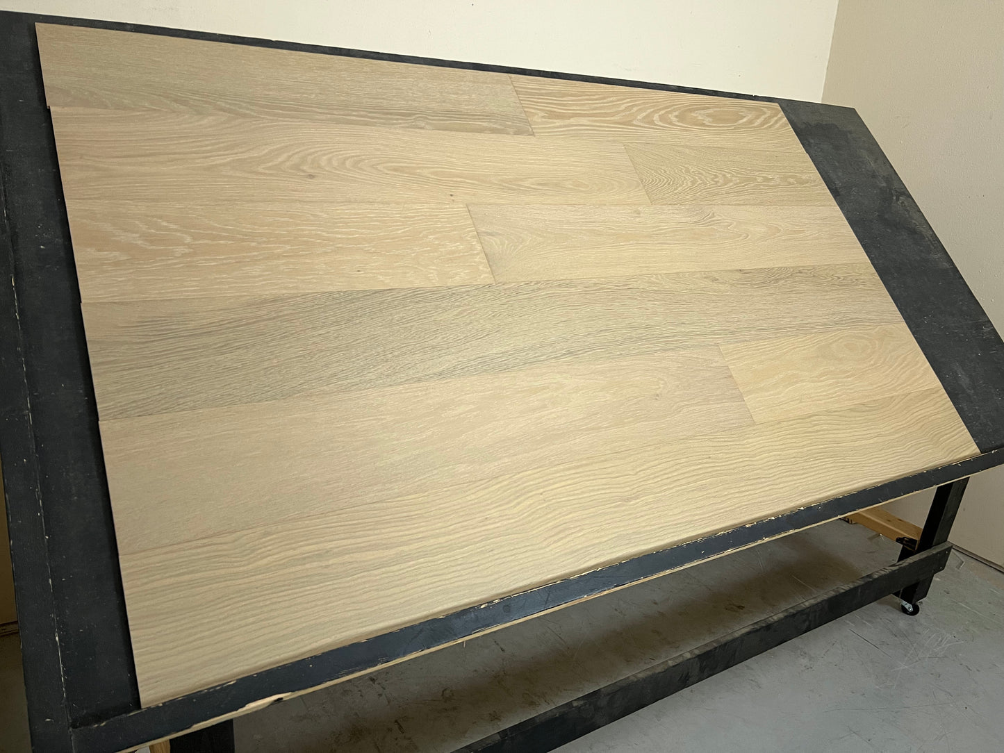 7 1/2" x 3/8" Engineered White Oak Amore Hardwood Flooring shown on a black shooting rack. shown from the left side.