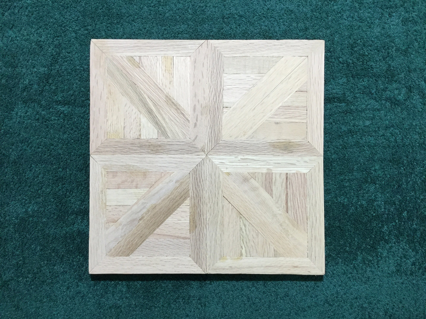 Unfinished Red Oak Canterbury Parquet Flooring Centered on a green background.