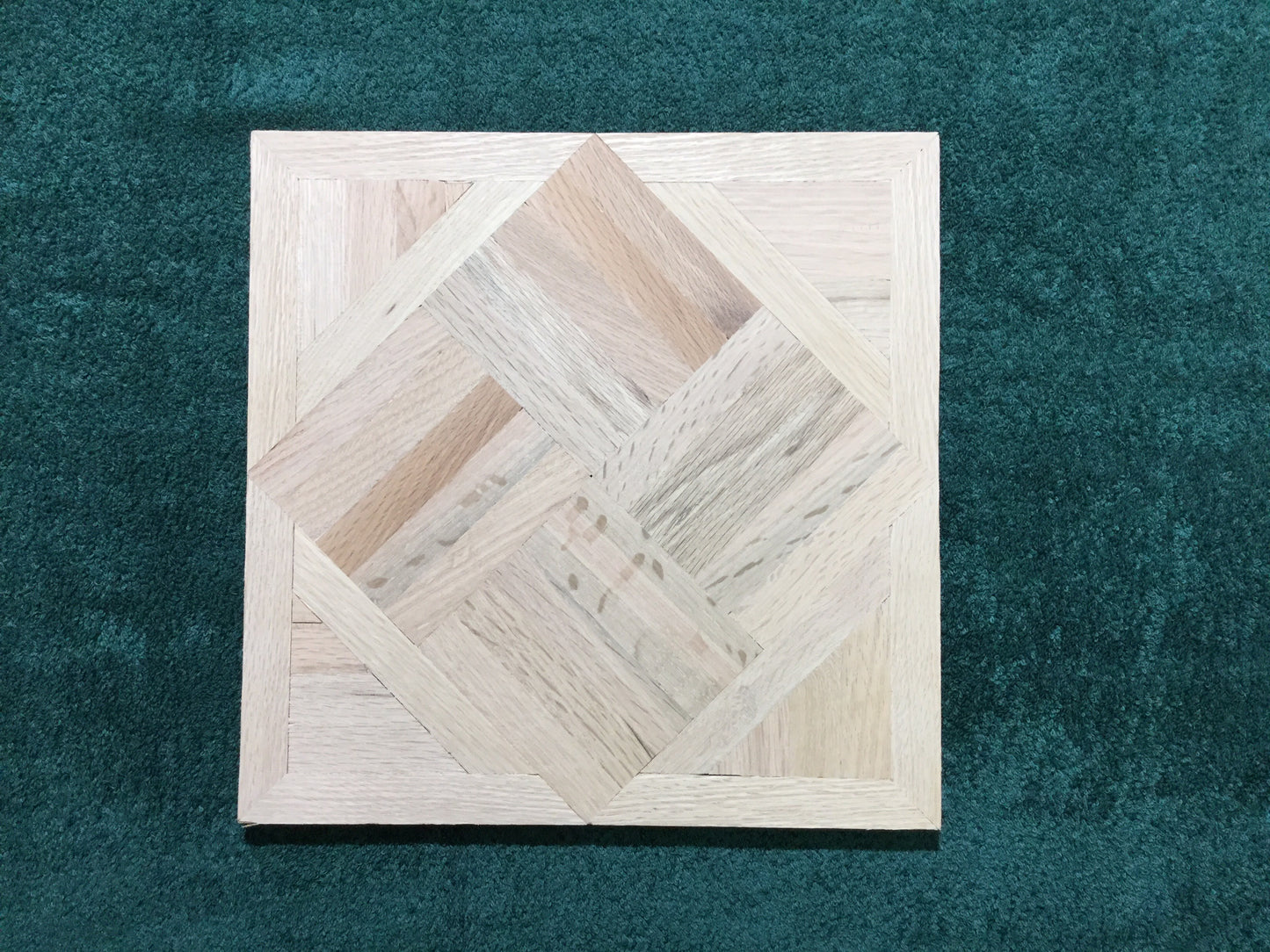 Unfinished Red Oak Chaucer Parquet Flooring shown centered, green back drop.