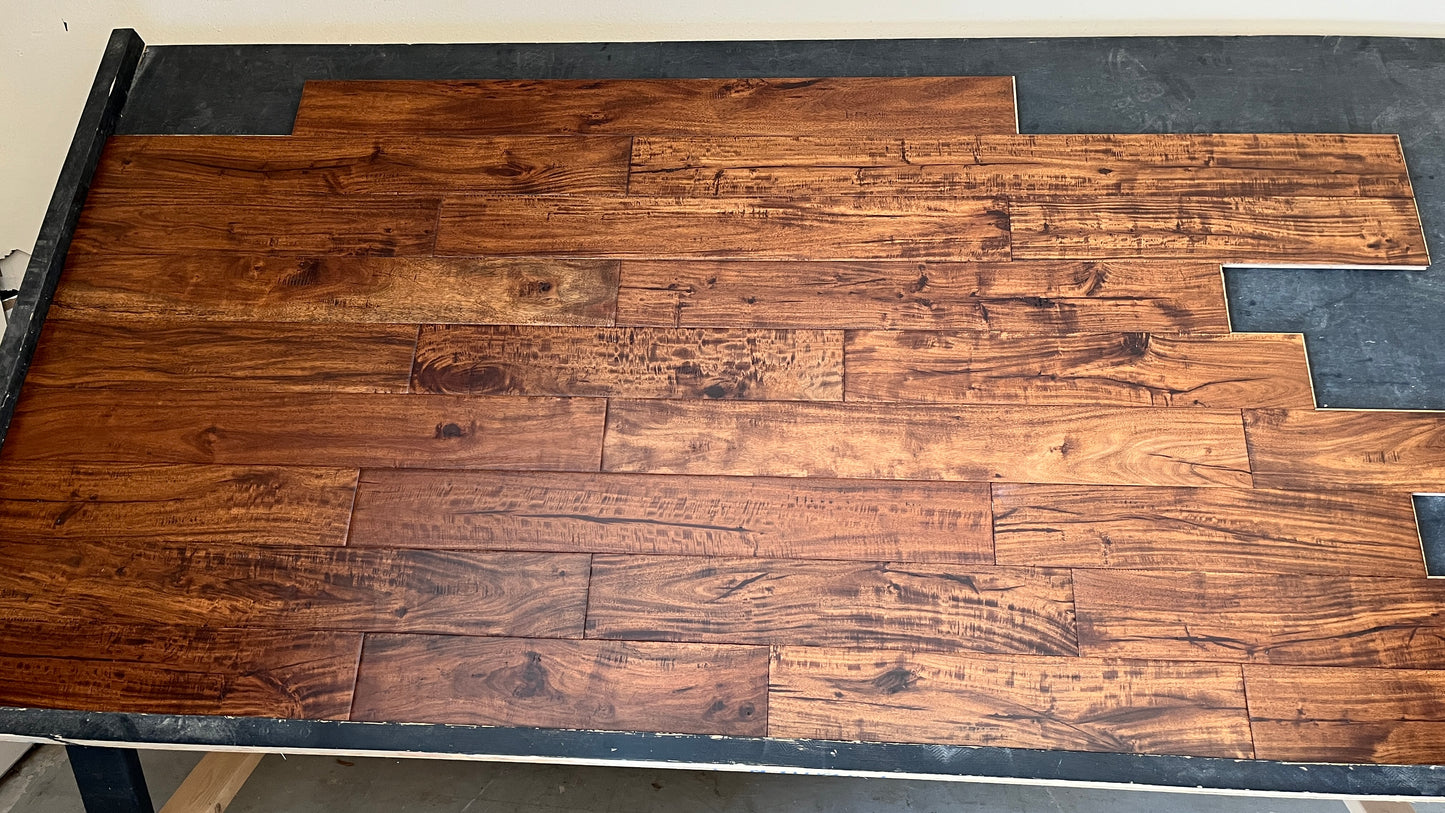 4 3/4" x 9/16" Engineered Acacia Toffee Hand-Scraped Hardwood Flooring on a black shooting rack head on