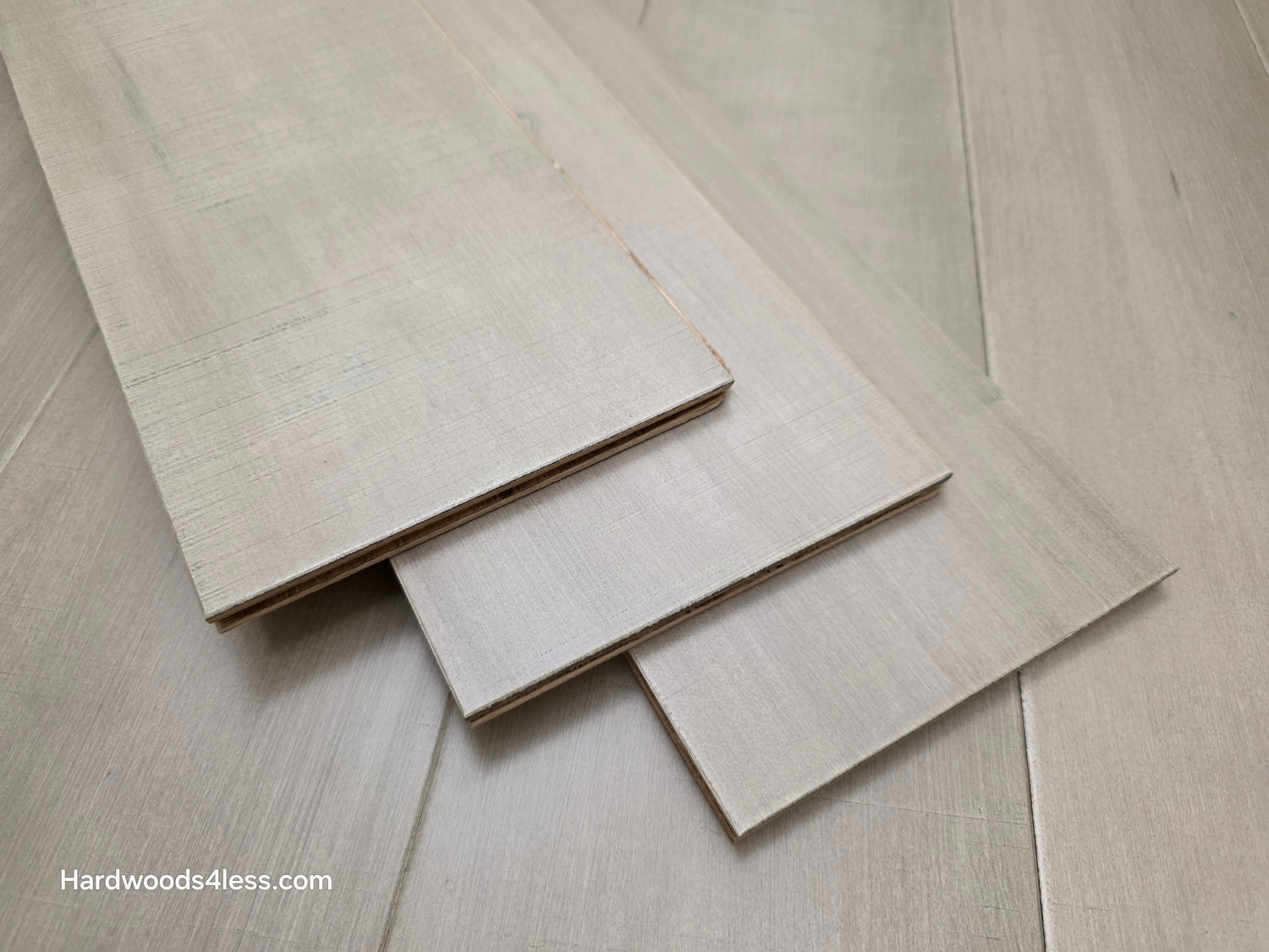 3 boards of maple hardwood flooring stacked on a maple floor 
