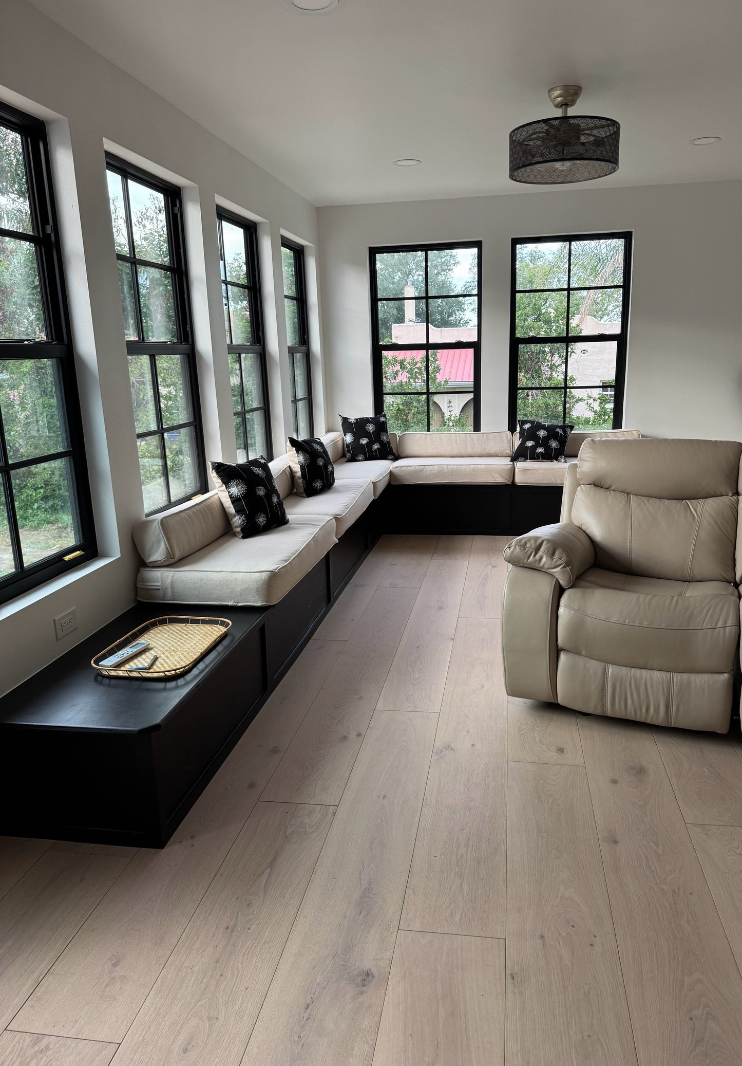 Here we have our 10.25" x 5/8" Engineered European Oak Shoal Creek Hardwood Flooring installed in a lovely sunroom. At the center, far side of the frame you see two big windows. On the left there are 4 big windows. Running along the wall back up against the windows you see a long sitting bench. On the right is a leather recliner.
