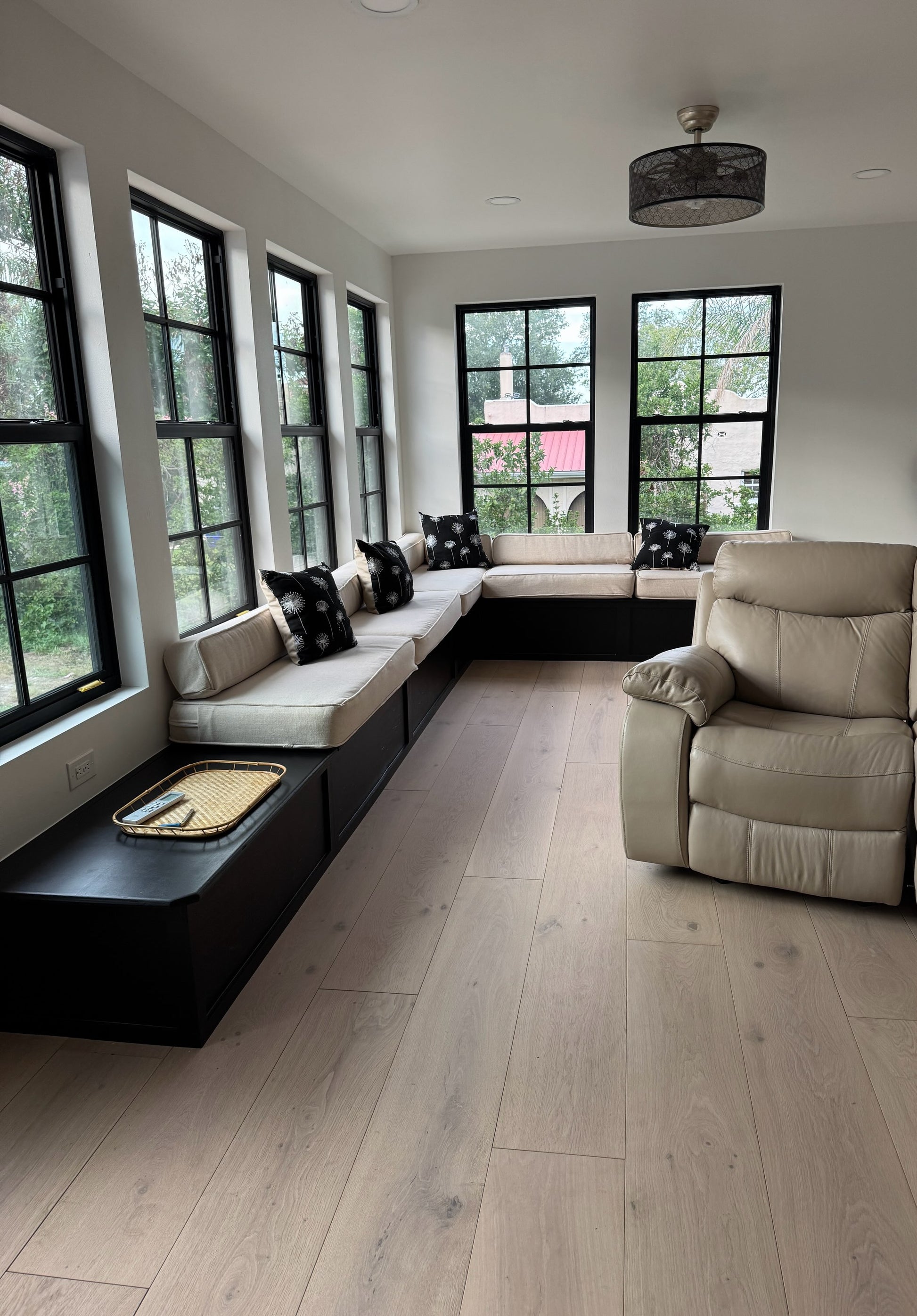 Here we have our 10.25" x 5/8" Engineered European Oak Shoal Creek Hardwood Flooring installed in a lovely sunroom. At the center, far side of the frame you see two big windows. On the left there are 4 big windows. Running along the wall back up against the windows you see a long sitting bench. On the right is a leather recliner.