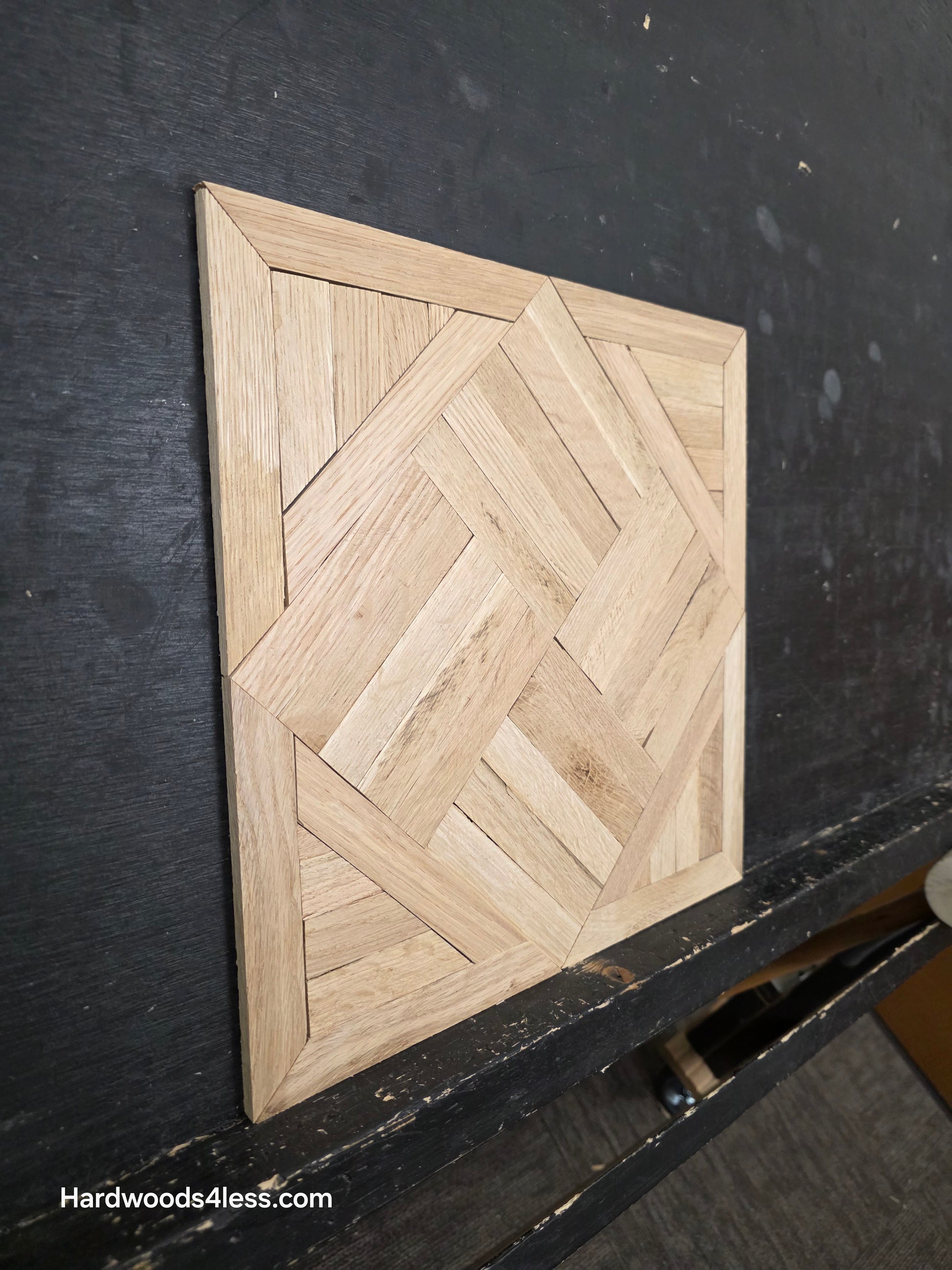 13 7/16" x 13 7/16" x 5/16" Unfinished White Oak Chaucer Parquet Flooring. Shown on a black shooting rack. Shot from steep left.