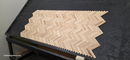 14 1/8" x 18 1/8" x 5/16" Unfinished White Oak Herringbone Parquet Flooring. 6 tiles wide on a black shooting table.