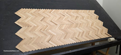 14 1/8" x 18 1/8" x 5/16" Unfinished White Oak Herringbone Parquet Flooring. 6 tiles wide on a black shooting table.