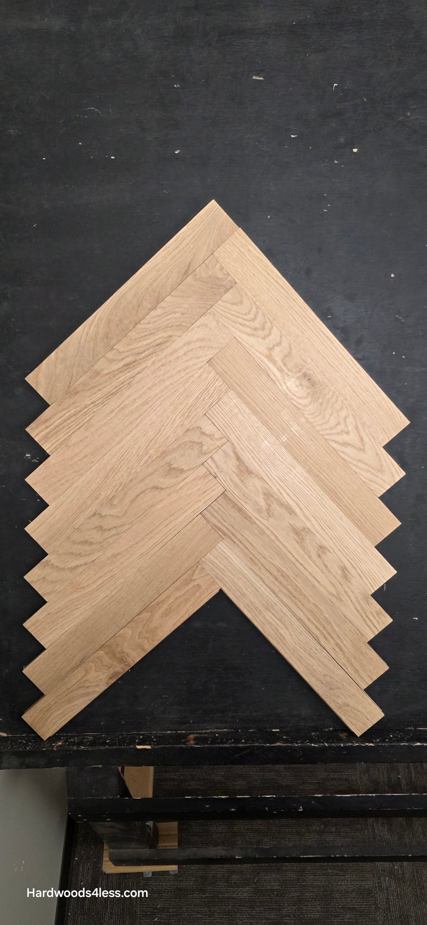 2 14 x 15.75 x 34 Solid Unfinished White Oak Herringbone Hardwood Flooring. Shown on a black shooting table. Shot from Center.