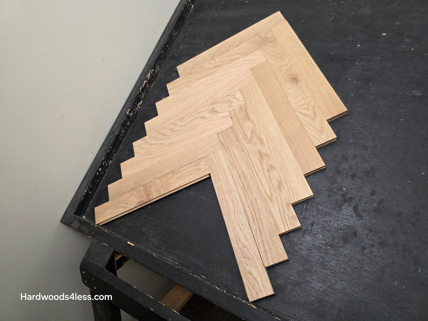 2 14 x 15.75 x 34 Solid Unfinished White Oak Herringbone Hardwood Flooring. Shown on a black shooting table. Shot from Center right.