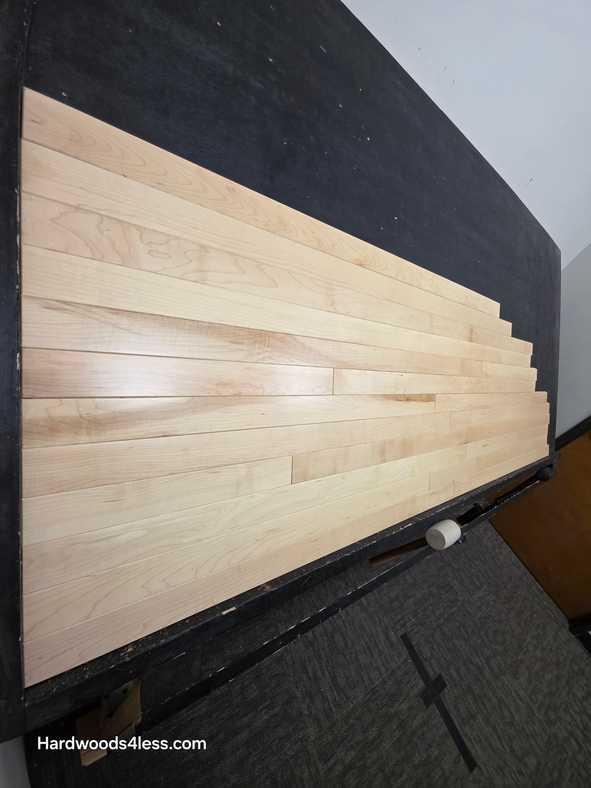 2 14 x 34 Natural Northern Maple Common & Better Hardwood Flooring. Shown on a black shooting rack. Shot steep left.