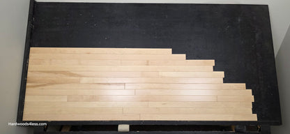 2 14 x 34 Natural Northern Maple Common & Better Hardwood Flooring. Shown on a black shooting table. shot from center. 