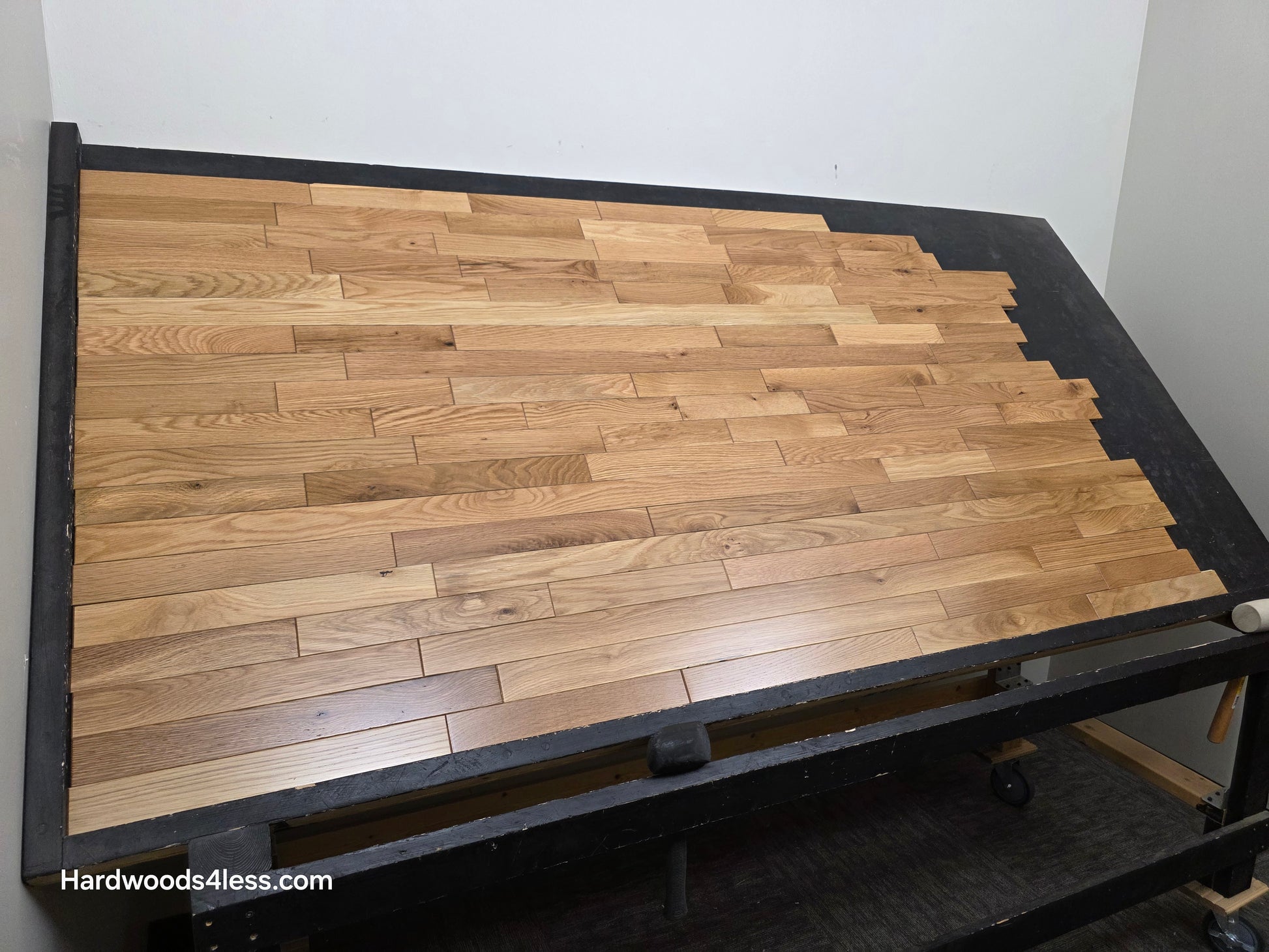2 1/4" x 3/4" Solid White Oak Natural Mill Run Hardwood Flooring. Shown on a black shooting table. Shot from low left.