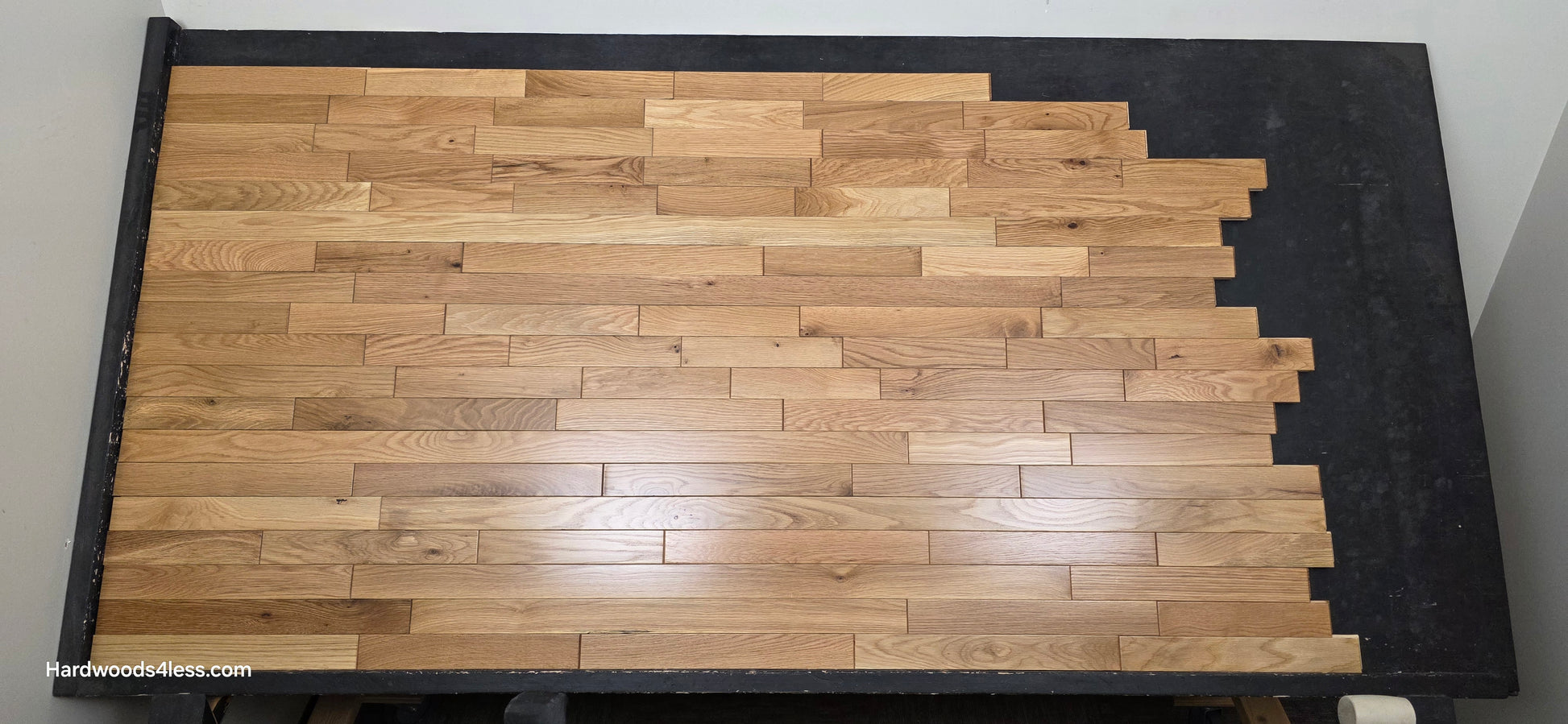 2 1/4" x 3/4" Solid White Oak Natural Mill Run Hardwood Flooring. Shown on a black shooting table. Shot from center.