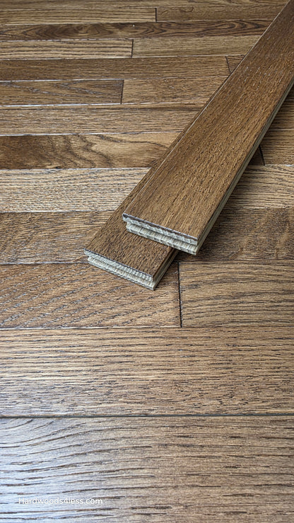 2 1/4" x 3/4" White Oak Gunstock Hardwood Flooring. shown as two boards stacked on top of the floor Hardwood floor. 