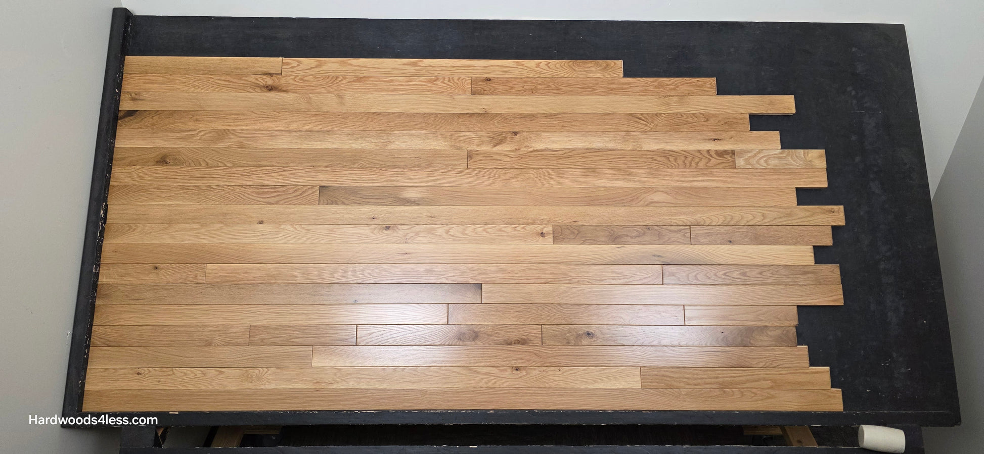 2 1/4" x 3/4" White Oak Natural #1 & Better Hardwood Flooring. Shown on a black shooting table. Center shot.