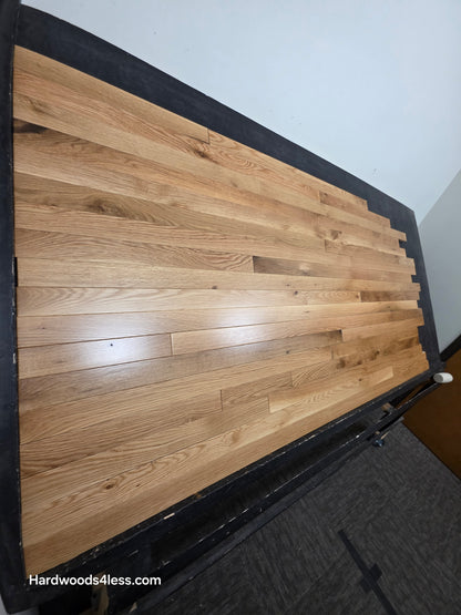 2 1/4" x 3/4" White Oak Natural #1 & Better Hardwood Flooring. Shown on a black shooting table. shot steep left.