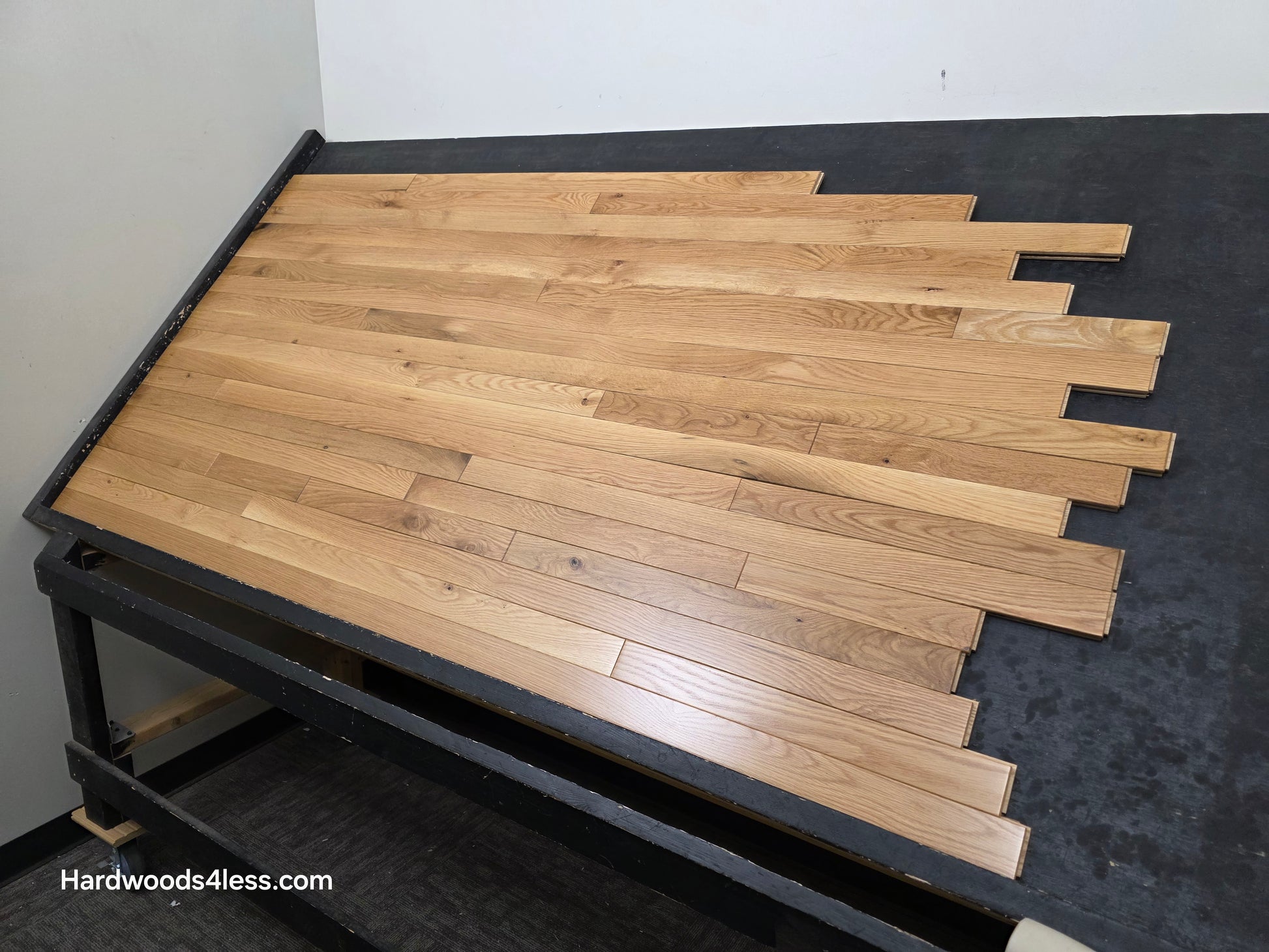 2 1/4" x 3/4" White Oak Natural #1 & Better Hardwood Flooring. Shown on a black shooting table. Shot from wide right. 