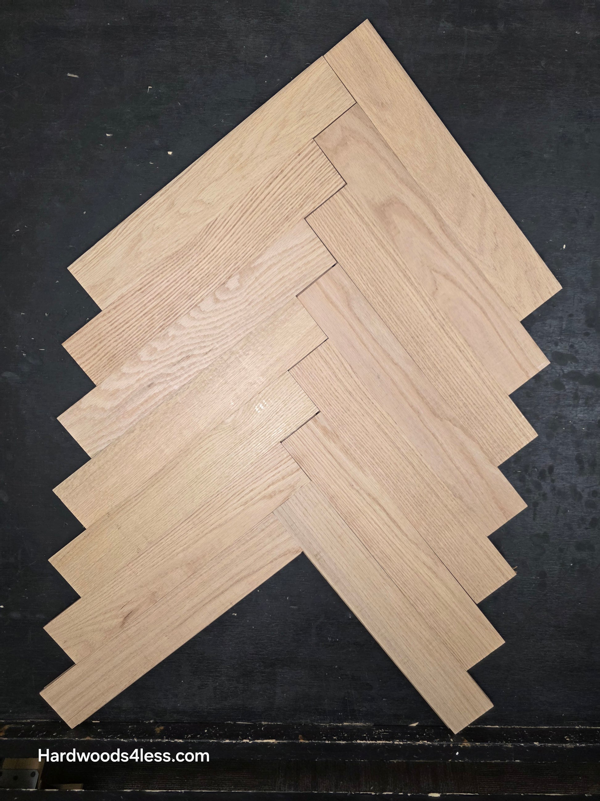 3 14 x 19 12 x 34 Solid Unfinished Red Oak Herringbone Hardwood Flooring. Shown on a black shooting table. Shot from Center.