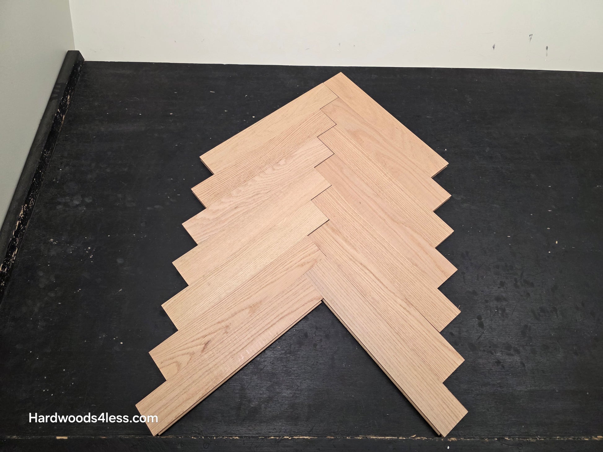 3 14 x 19 12 x 34 Solid Unfinished Red Oak Herringbone Hardwood Flooring. Shown on a black shooting table. Shot from Center.