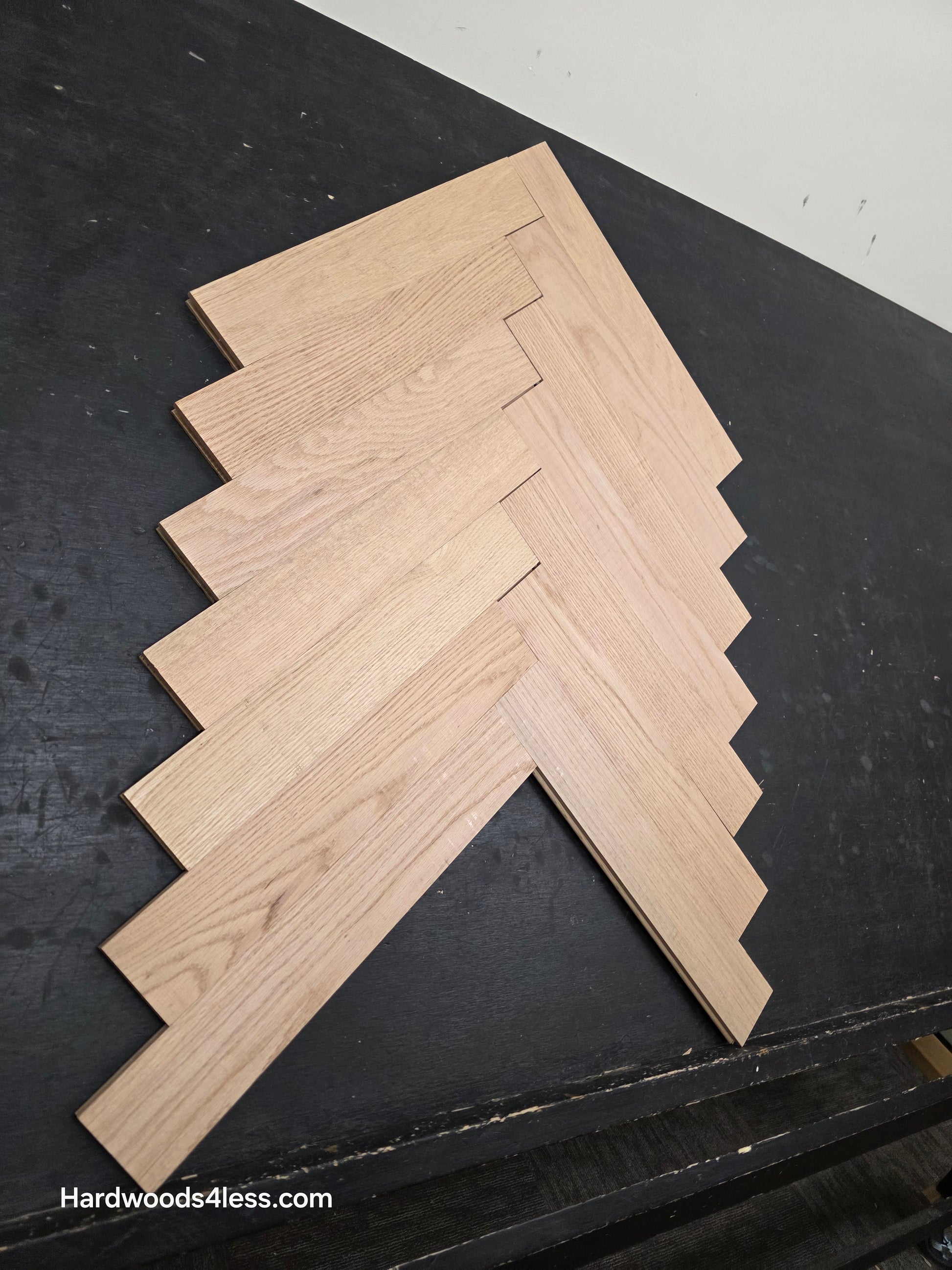 3 14 x 19 12 x 34 Solid Unfinished Red Oak Herringbone Hardwood Flooring. Shown on a black shooting table. Shot from steep left.