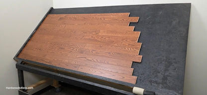 3 1/4" x 3/4" Red Oak Butterscotch Common & Better Hardwood Flooring. Shown on a black shooting table. Shot from wide right.