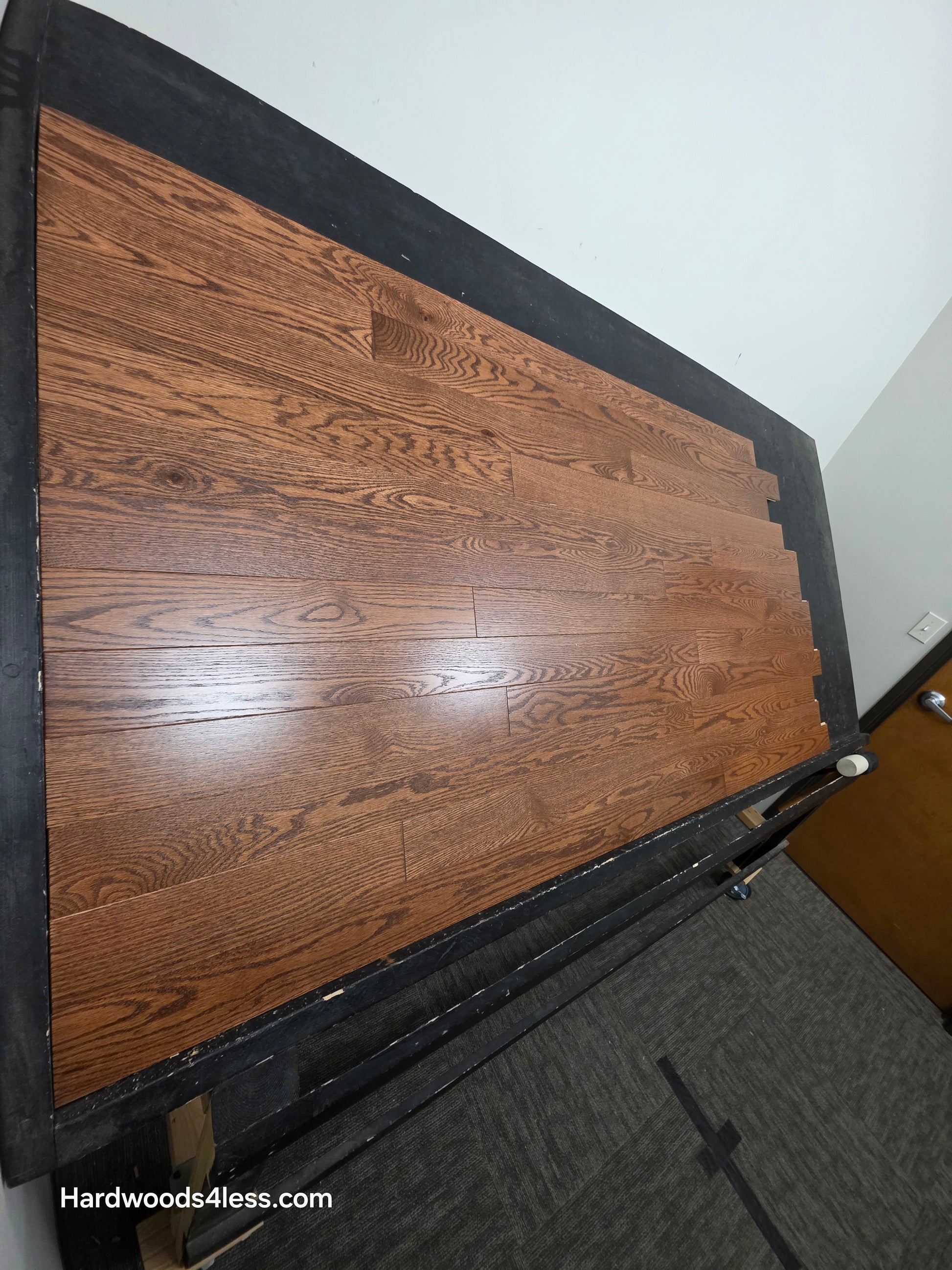 3 1/4" x 3/4" Red Oak Butterscotch Common & Better Hardwood Flooring. Shown on a black shooting table. Shot from steep left. 