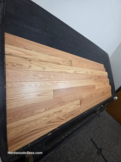 3 1/4" x 3/4" Red Oak Natural Common & Better Low Gloss Hardwood Flooring. shown on a black shooting table. Shot from steep left. 
