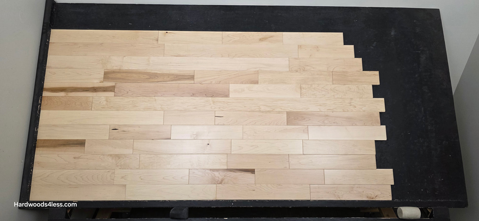 3 1/4" x 3/4" Solid Maple Natural Rustic Shorts Hardwood Flooring. Shown on a black shooting table. Shot from center.