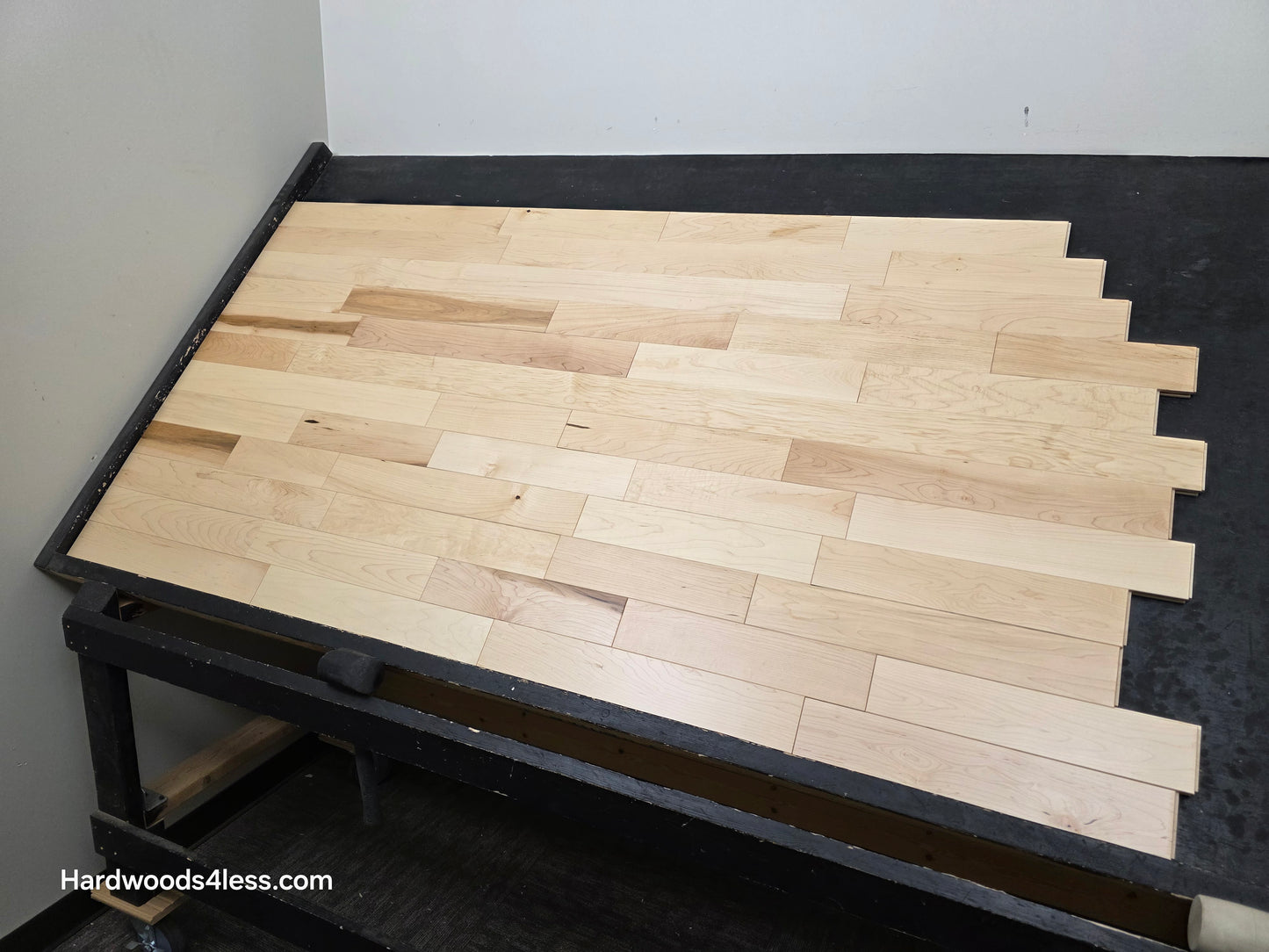 3 1/4" x 3/4" Solid Maple Natural Rustic Shorts Hardwood Flooring. Shown on a black shooting table. Shot from wide right.