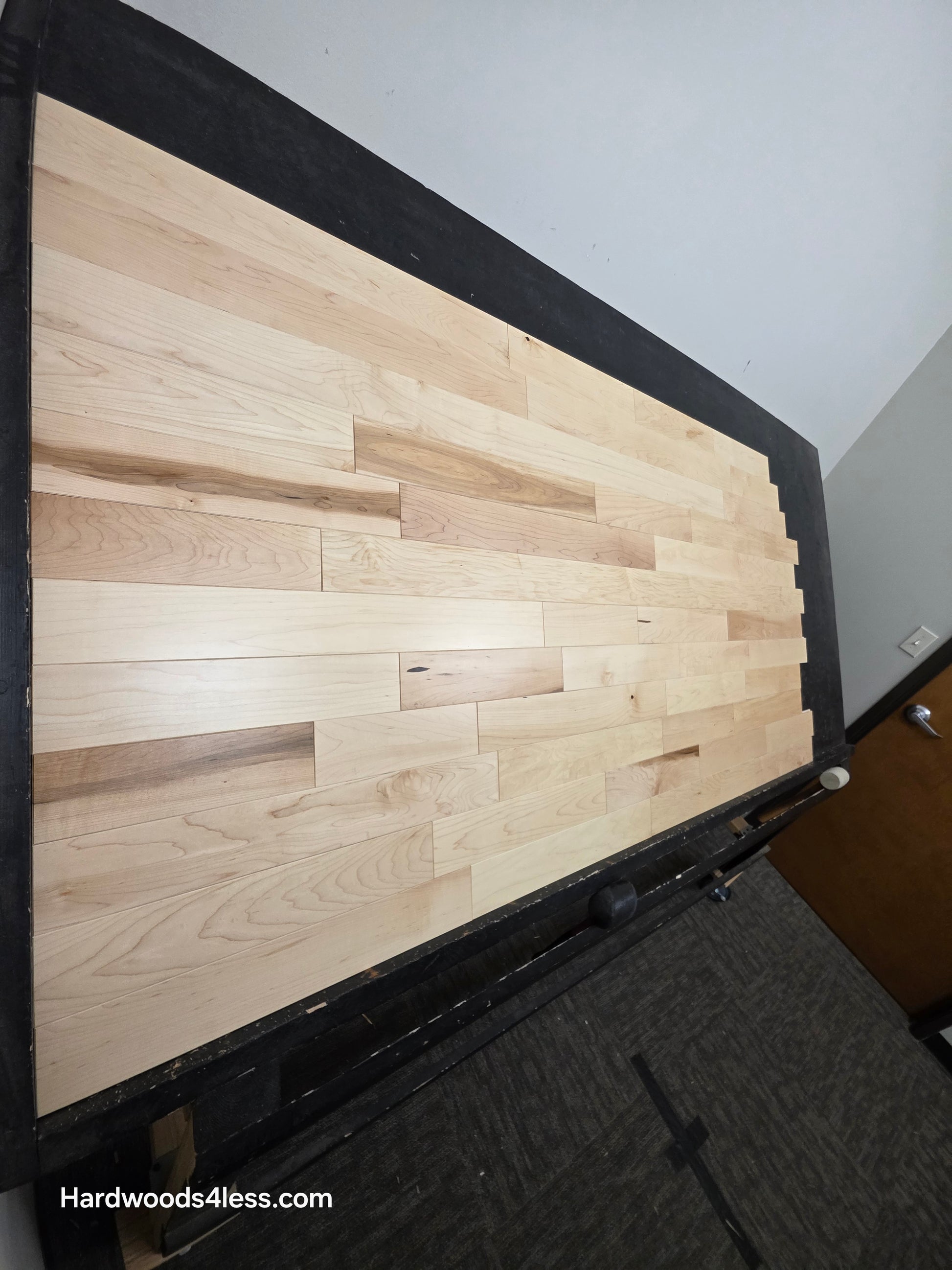 3 1/4" x 3/4" Solid Maple Natural Rustic Shorts Hardwood Flooring. Shown on a black shooting table. Shot from steep left.