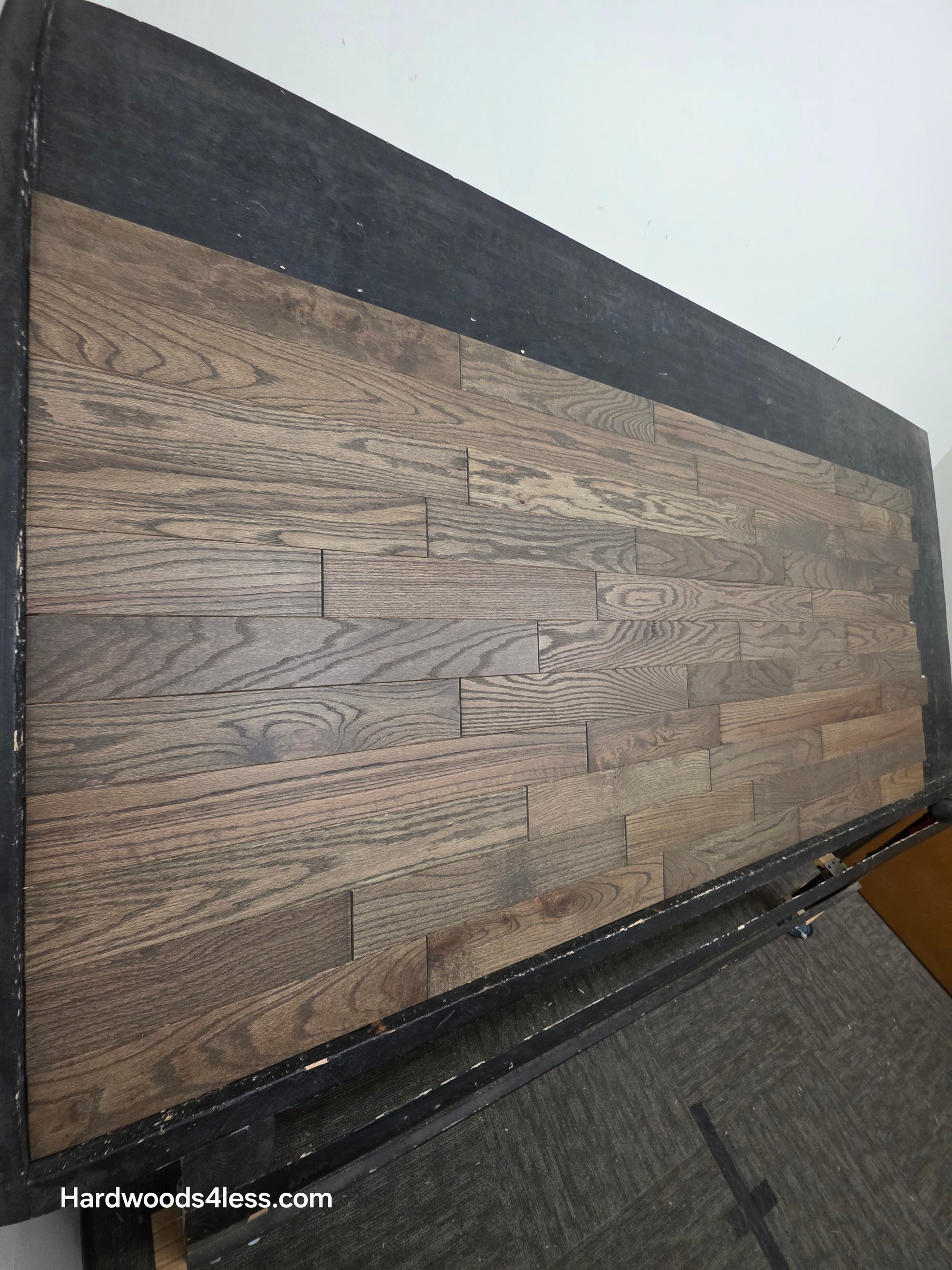 3 1/4" x 3/4" Solid Red Oak Coal Hardwood Flooring. Shown on a black shooting table. shot wide left. 