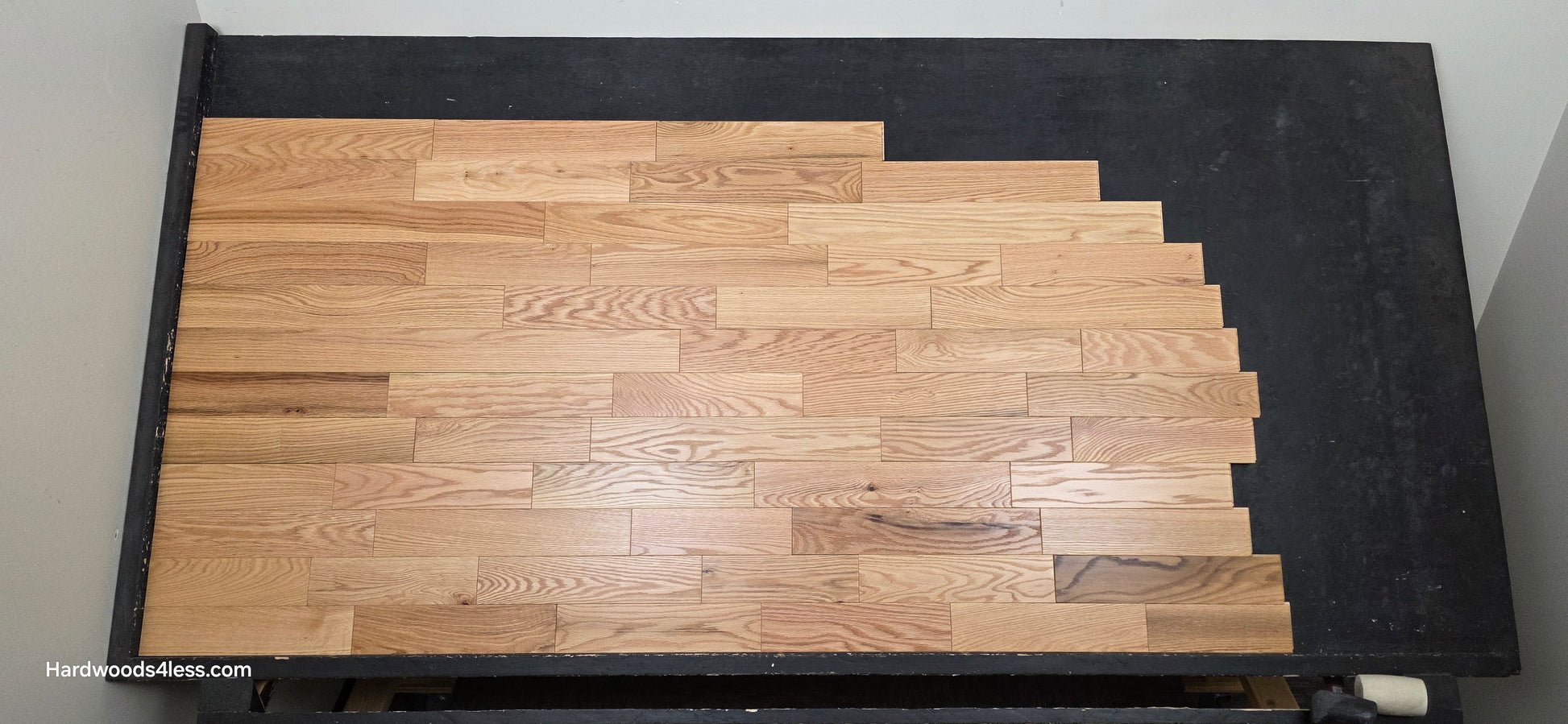 3 1/4" x 3/4" Solid Red Oak Natural Rustic Shorts Hardwood Flooring. Shown on a black shooting table. Shot from center.