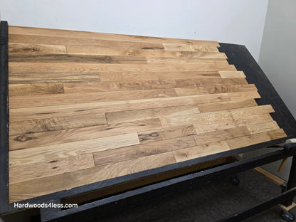 3 1/4" x 3/4" Solid White Oak Natural Character Grade Hardwood Flooring. Shown on a black shooting table. Wide left angle shot.