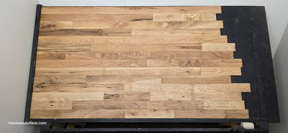 3 1/4" x 3/4" Solid White Oak Natural Character Grade Hardwood Flooring. Shown on a black shooting table. Shot from center. 