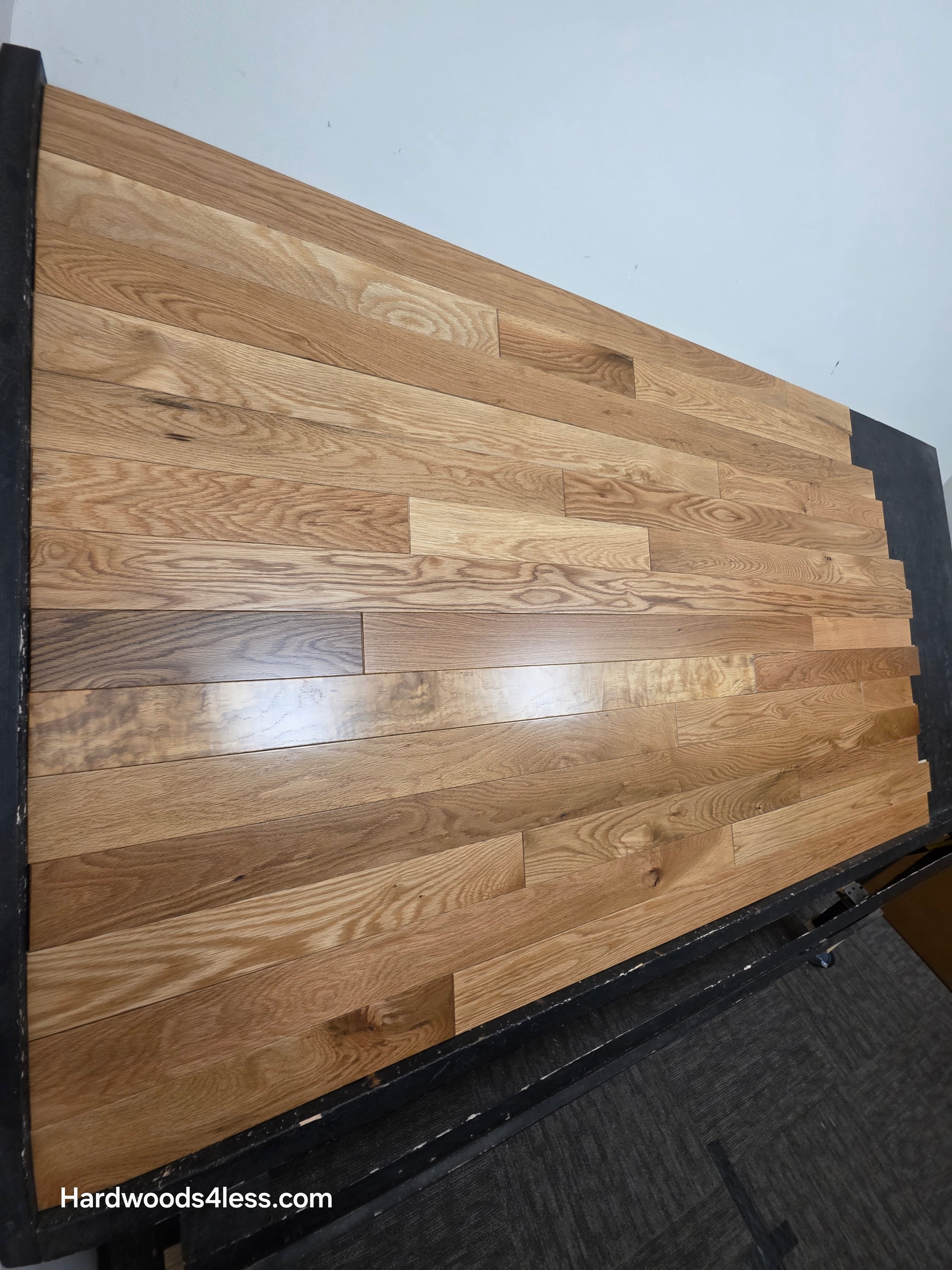 3 1/4" x 3/4" White Oak Natural Hardwood Flooring. Shown on a black shooting table. Steep left angle shot.