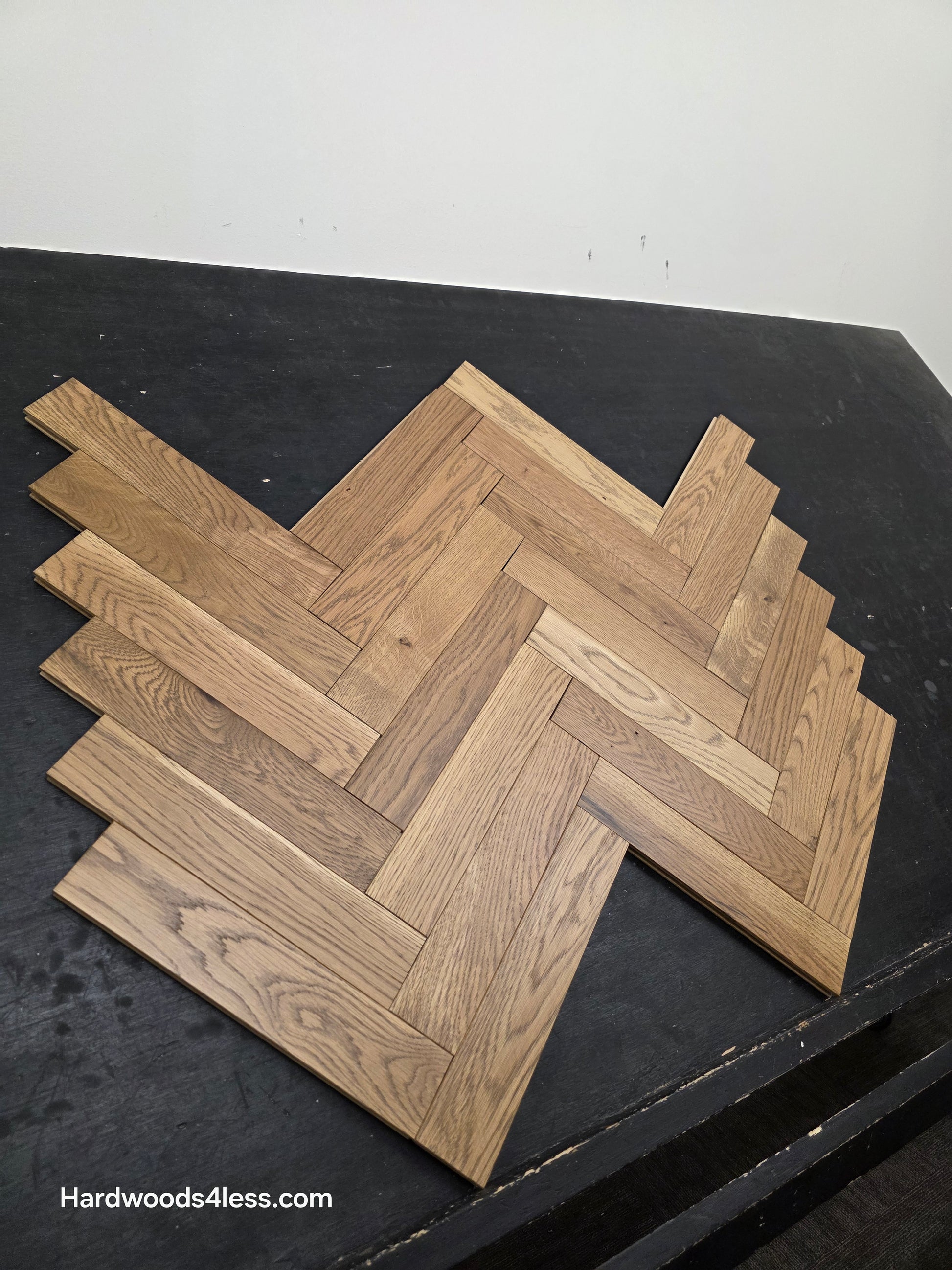 3" x 15" x 3/4" Solid White Oak Newport Herringbone Hardwood Flooring. Shown on a black shooting table. shot from the left.