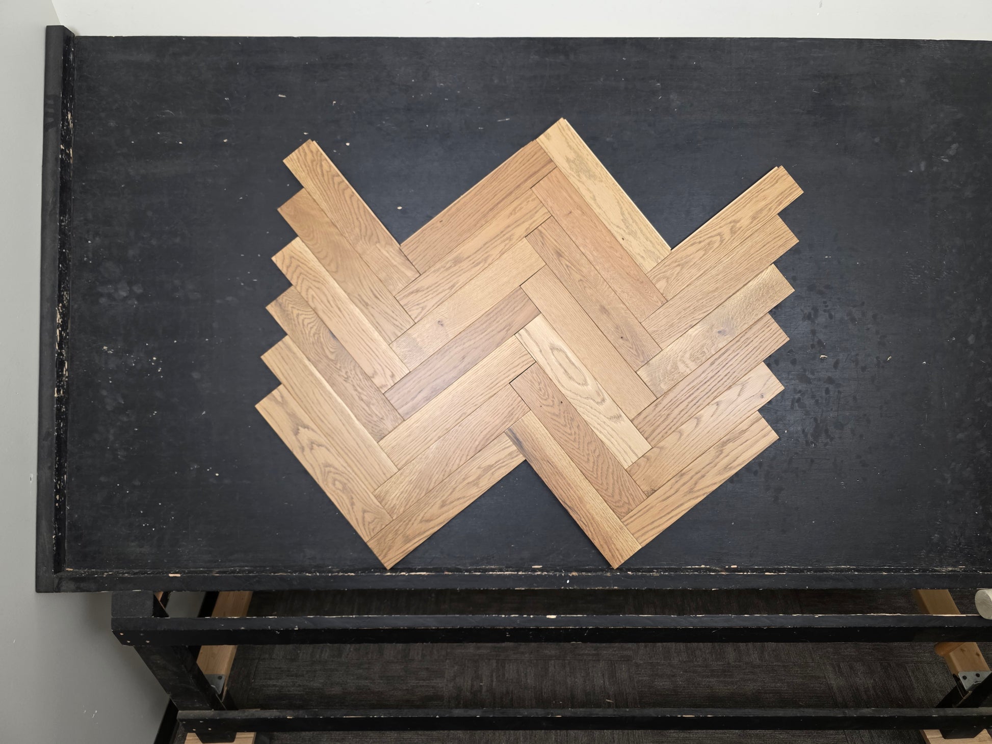 3" x 15" x 3/4" Solid White Oak Newport Herringbone Hardwood Flooring. Shown on a black shooting table. center shot.