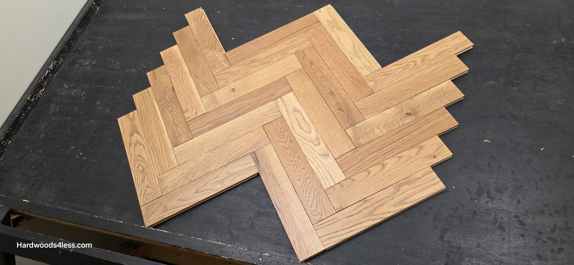 3" x 15" x 3/4" Solid White Oak Newport Herringbone Hardwood Flooring. Shown on a black shooting table. Shot low wide right. 