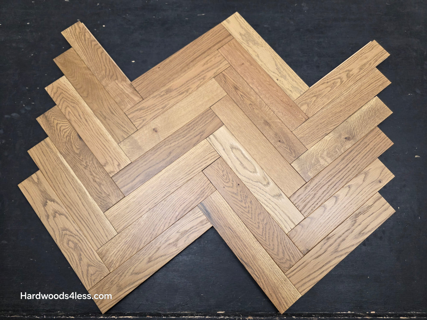 3" x 15" x 3/4" Solid White Oak Newport Herringbone Hardwood Flooring. Shown on a black shooting table. Close up.