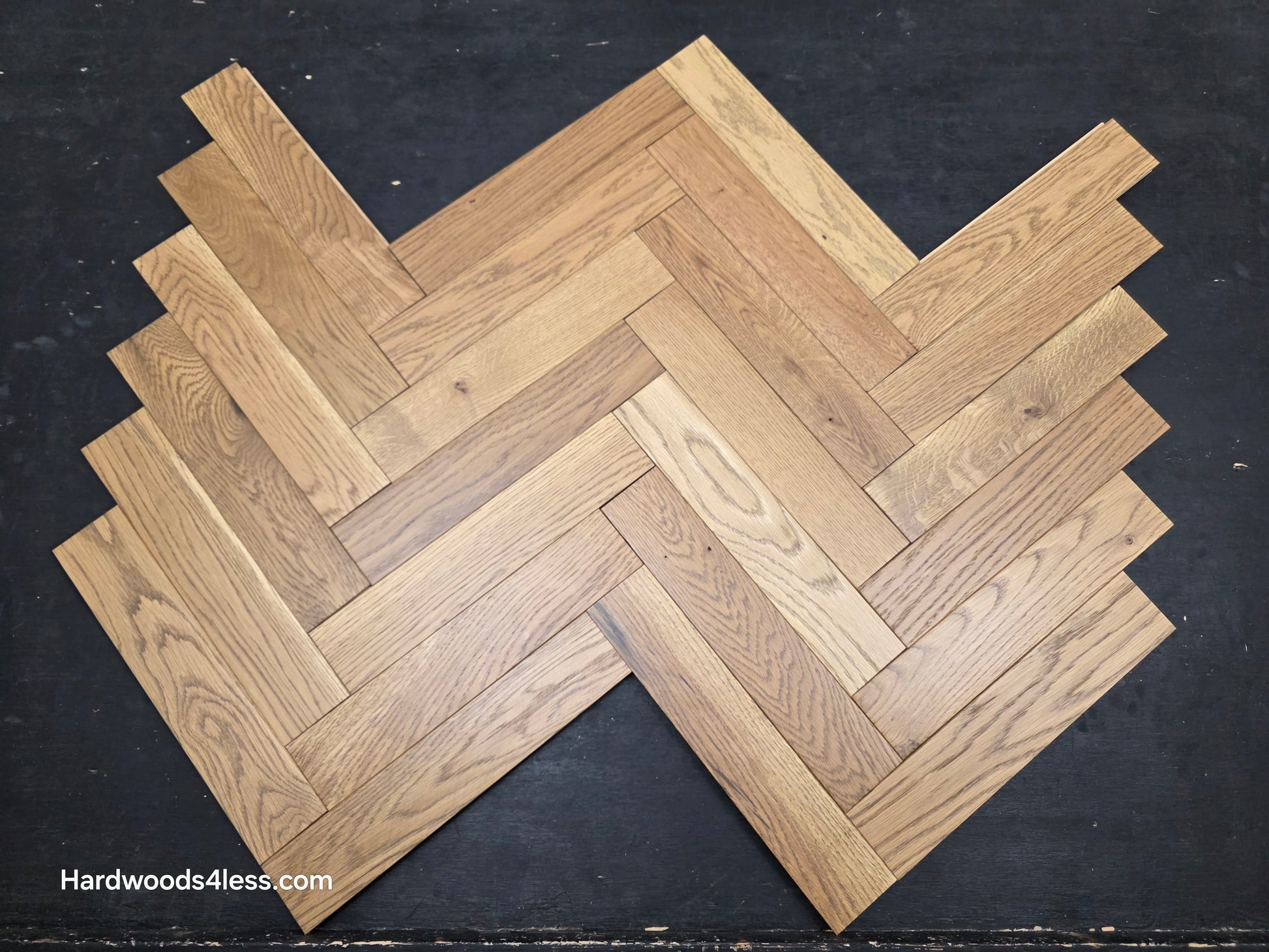 3" x 15" x 3/4" Solid White Oak Newport Herringbone Hardwood Flooring. Shown on a black shooting table. Close up.