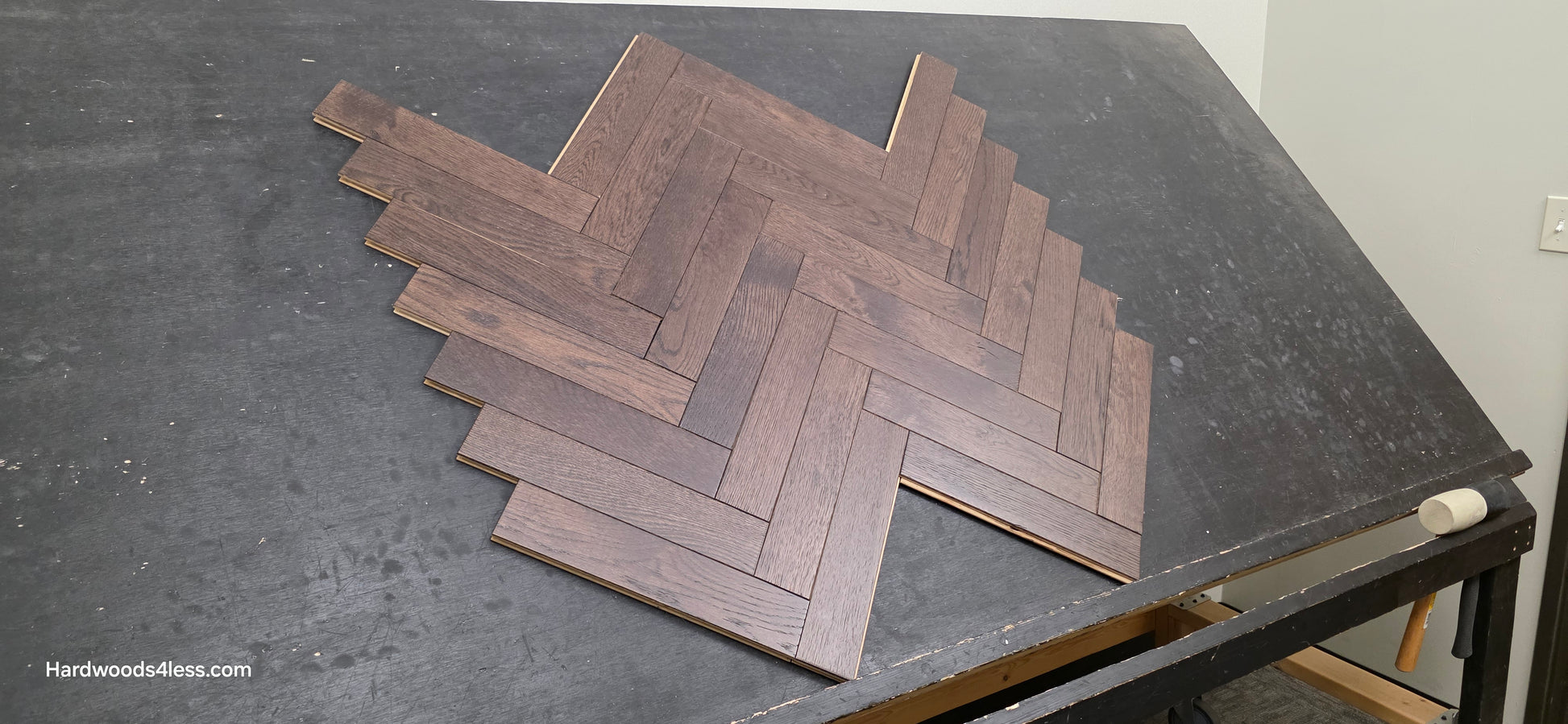 3" x 15" x 3/4" Solid White Oak Salem Herringbone Hardwood Flooring. Shown on a black shooting table. Close up.