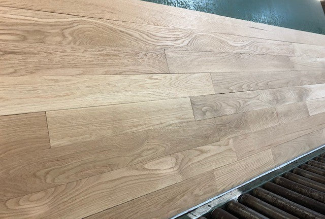 4 x 3/4 Unfinished White Oak Select & Better Solid Hardwood Flooring left side picture. On a green rack with black rollers