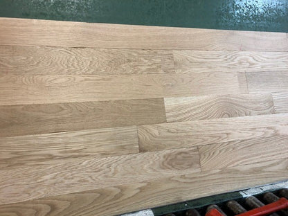 4 x 3/4 Unfinished White Oak Select & Better Solid Hardwood Flooring on a green shooting rack with black rollers. head on shot