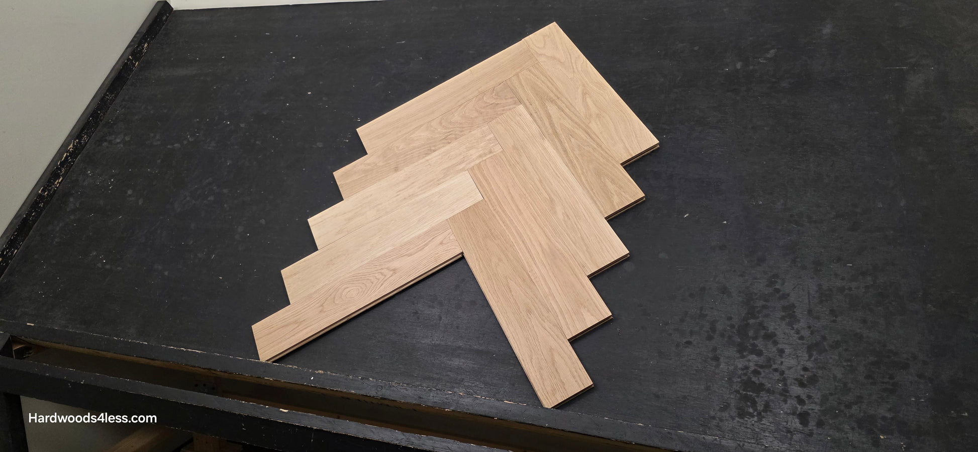 4" x 20" x 3/4" Solid Unfinished White Oak Herringbone Hardwood Flooring. Shown on a black shooting table. Shot from low right.