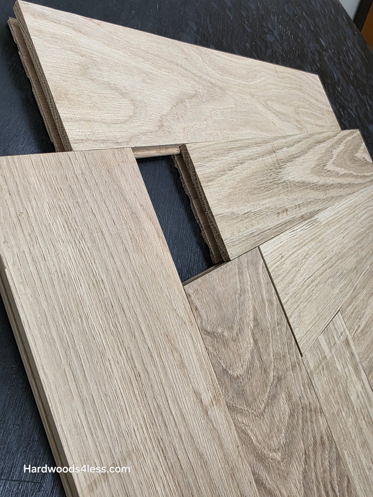 4" x 20" x 3/4" Solid Unfinished White Oak Herringbone Hardwood Flooring. Shown on a black shooting table. Shot very close up. To highlight the grooves. 