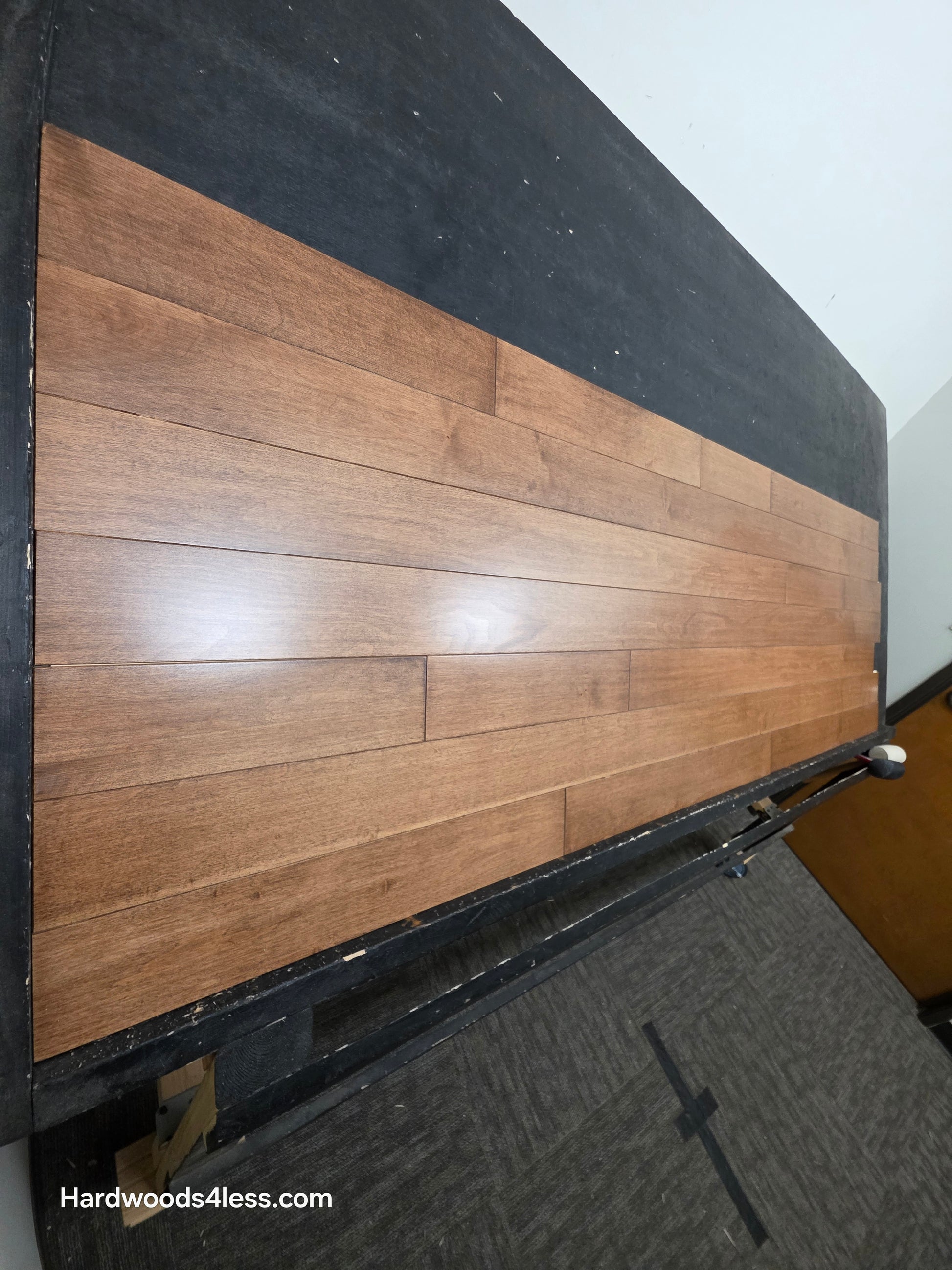 4" x 3/4" Solid Maple Hazelnut Hardwood Flooring. Shown on a black shooting table. Shot from steep left.