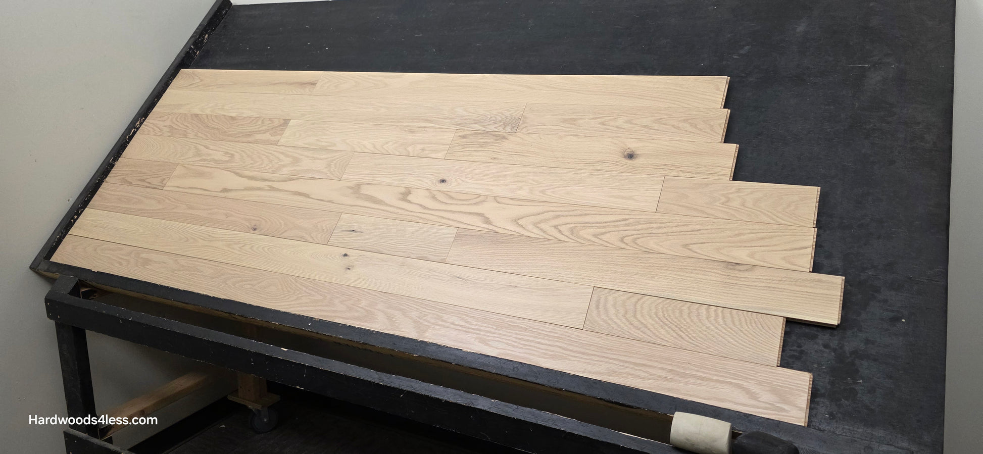 4" x 3/4" Solid Red Oak Doe Hardwood Flooring. Shown on a black shooting table. Shot from wide right.