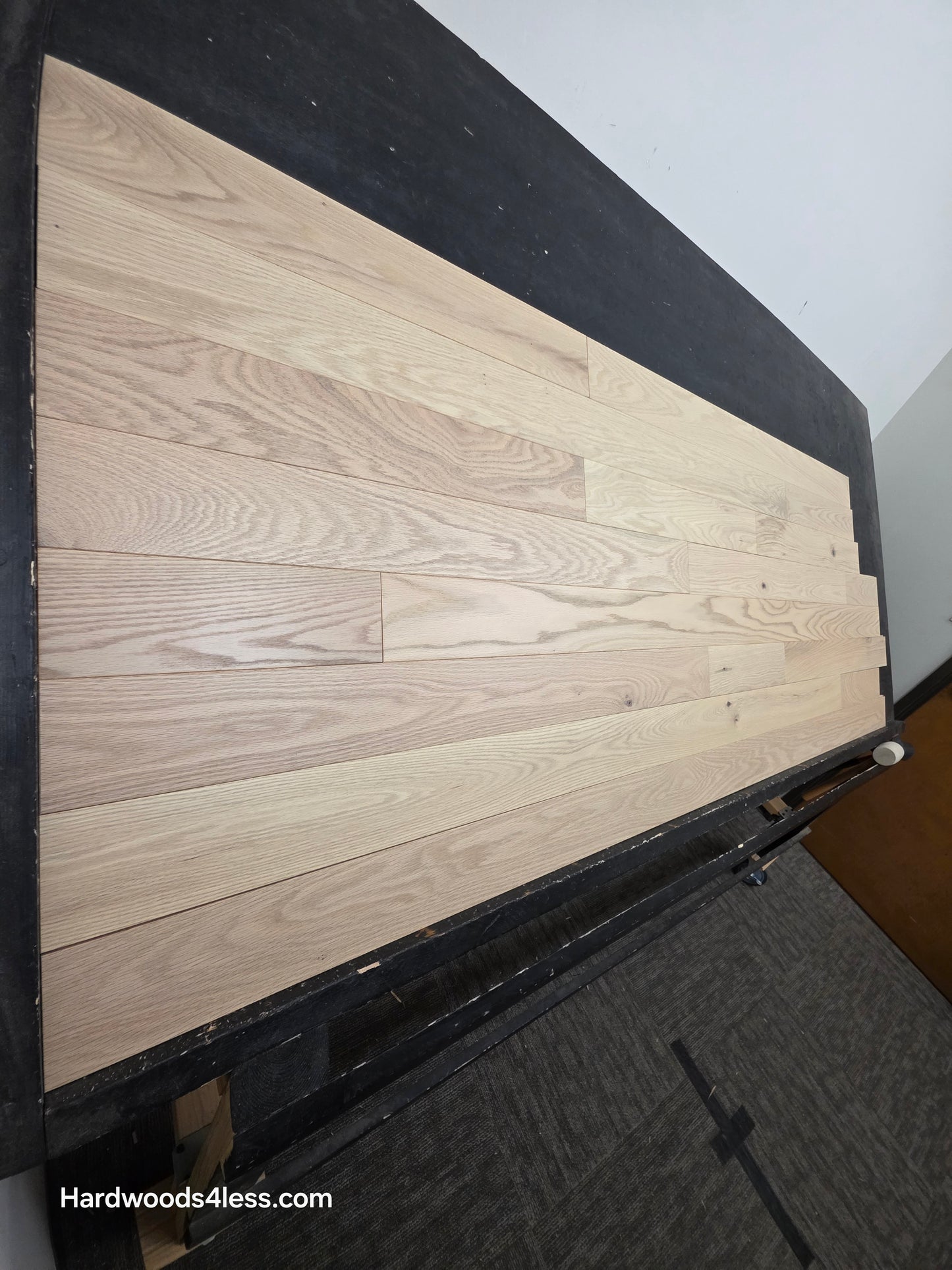 4" x 3/4" Solid Red Oak Doe Hardwood Flooring. Shown on a black shooting table. Shot from steep left.